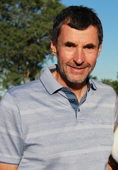 Geschäftsleiter und Präsident des Marco Polo Golfclubs auf dem Golfplatz. er trägt ein hellblaues Polo-Shirt und lächelt.